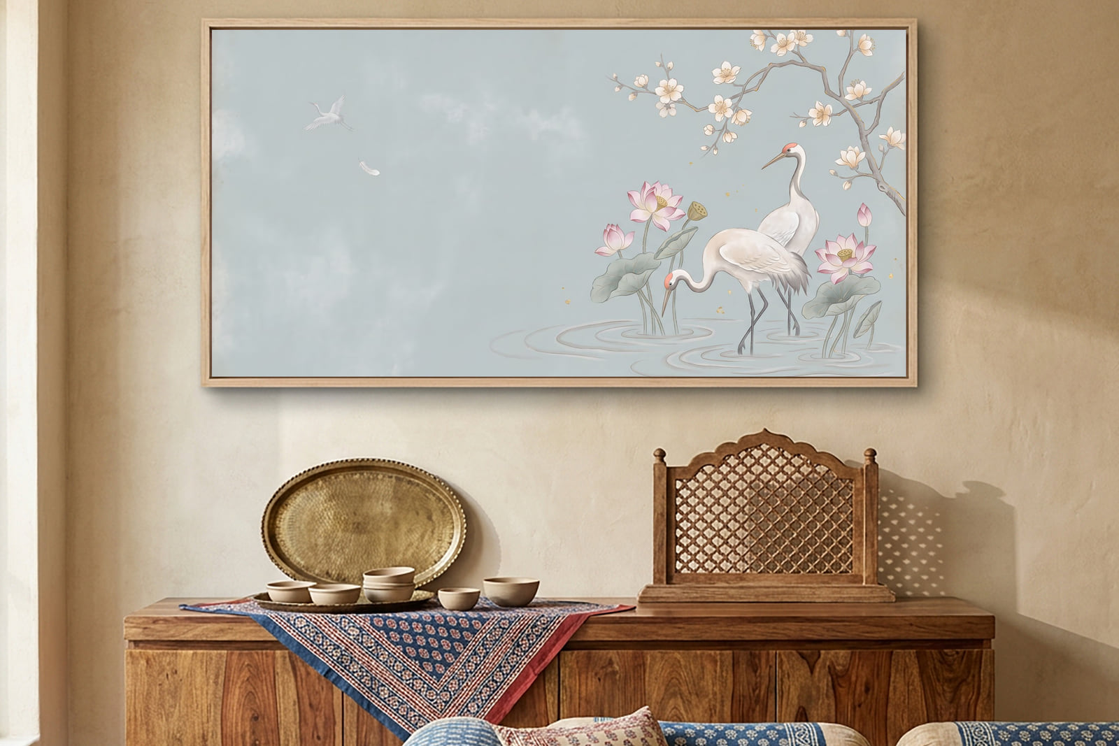 A wide Pichwai canvas of sarus cranes over a lotus pond, hung above a sideboard